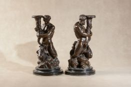 A pair of patinated bronze figural candelabra bases cast as tritons