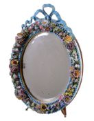 An English porcelain flower encrusted oval looking glass frame with wood easel stand