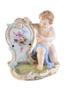 A Meissen menu holder modelled as a kneeling putto with shield