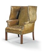 A George III mahogany and nailed leather upholstered wing armchair, late 18th century, on square