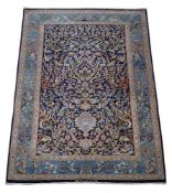 An Isfahan rug, part silk, the dark blue central field decorated with profusely growing foliage,