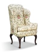 A George II style mahogany and walnut wing armchair, the shaped back with out scrolled arms and