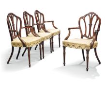 A set of four George III carved mahogany armchairs, late 18th century, the arched shield shaped