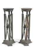 A pair of green painted torchere stands in Egyptian Revival taste, 20th century, the circular tops