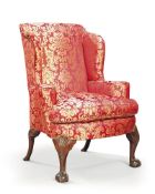 A George II walnut wing armchair, mid-18th century, upholstered in red and gold damask, the front