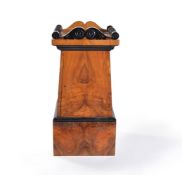 A Biedermeier style walnut and ebonised pedestal cupboard, of trapezoid section, the scrolled and