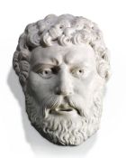 A relief sculpted white marble wall fount modelled as a bearded male visage, possibly a river god,