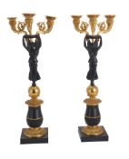 A pair of patinated and parcel gilt metal three light figural candelabra in Empire style