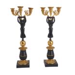 A pair of patinated and parcel gilt metal three light figural candelabra in Empire style