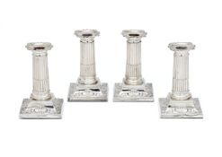 A set of four Edwardian silver short columnar candlesticks by The Goldsmiths & Silversmiths Co. Ltd