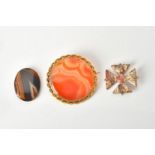 Three hardstone brooches:- a mottled hardstone Maltese Cross brooch