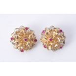 A pair of ear clips of abstract bombé design claw set with five round cut pinkish-red stones