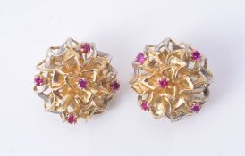 A pair of ear clips of abstract bombé design claw set with five round cut pinkish-red stones