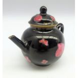 Small famille rose Quianlong globular teapot with leaves and flower heads on a black ground H8.5cms.