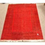 Pakistani Bokhara design red ground carpet, field decorated with small repeating Gul motifs,