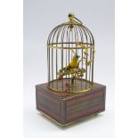 Clockwork automated singing bird music box with brass cage on rectangular base with incised