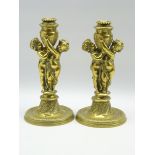 Pair gilt metal candlesticks modelled as standing putti holding an urn shaped vase on moulded