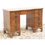 Reprodux mahogany desk, shaped top with leather inset, nine drawers, on bracket feet, W115cm, H75cm,