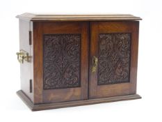 Early 20th century oak smoker cabinet with carved panel doors, fitted interior with tobacco jar,