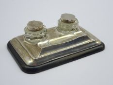 Small silver inkstand with 2 covered silver mounted glass inkwells and pen rest on an ebonised base