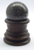 Carved granite sphere supported by a 19th century turned wood stand,