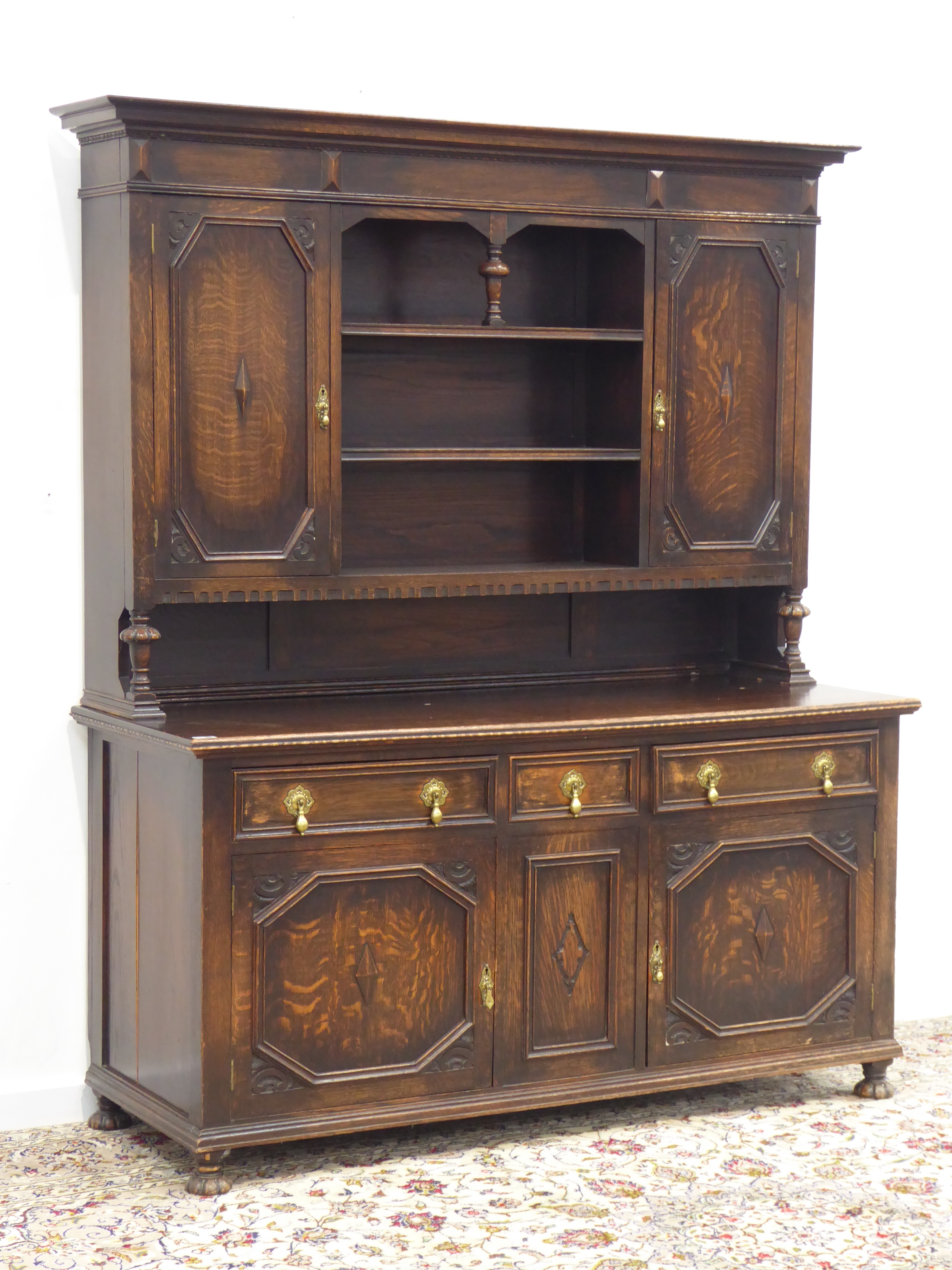 Early 20th century oak dresser, projecting cornice above two geometric cupboards and centre shelves,