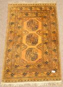 Afghan Bokhara gold ground rug, with three central Gul motifs, repeating geometric borders,