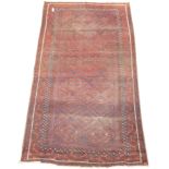 Old Afghan red ground carpet, field decorated with lozenge design, repeating geometric border,