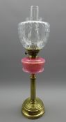 Table oil lamp with pink glass reservoir on a fluted brass column and with glass shade H63cms