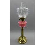 Table oil lamp with pink glass reservoir on a fluted brass column and with glass shade H63cms