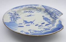 18th Century English Delft charger decorated in blue and white with a Chinese figure, dog,