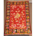 Red ground kilim rug, decorated with colourful stylised motifs,