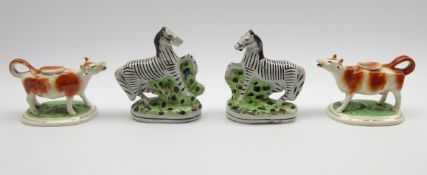 Pair of 19th Century pottery cow creamers with sponged orange decoration,