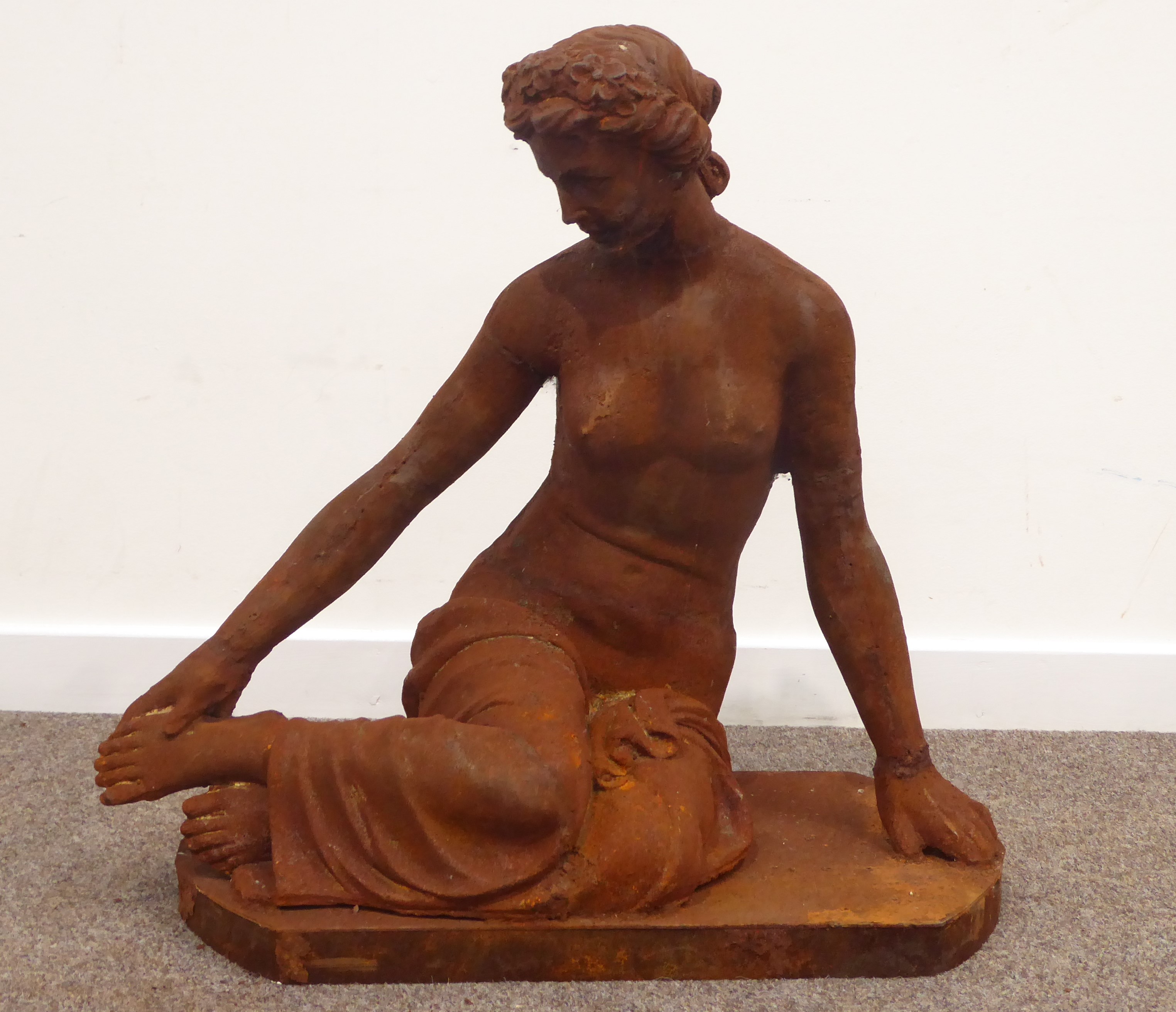 Cast iron classical garden figure of a semi-nude seated maiden,