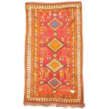 Tribal woollen red ground rug, quadruple lozenge medallion, stylised motifs, repeating boarder,