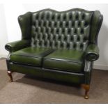 Georgian style two seat wing back settee, upholstered in deeply buttoned green leather,