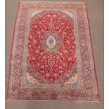 Large Persian Kashan finely knotted ground rug, blue floral medallion and spandrels on red field,