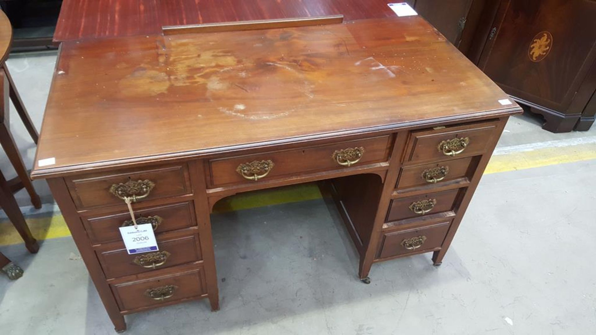 A Kneehole Office Desk with nine drawers featuring brass fixings all on castor wheels (H 75cm, W