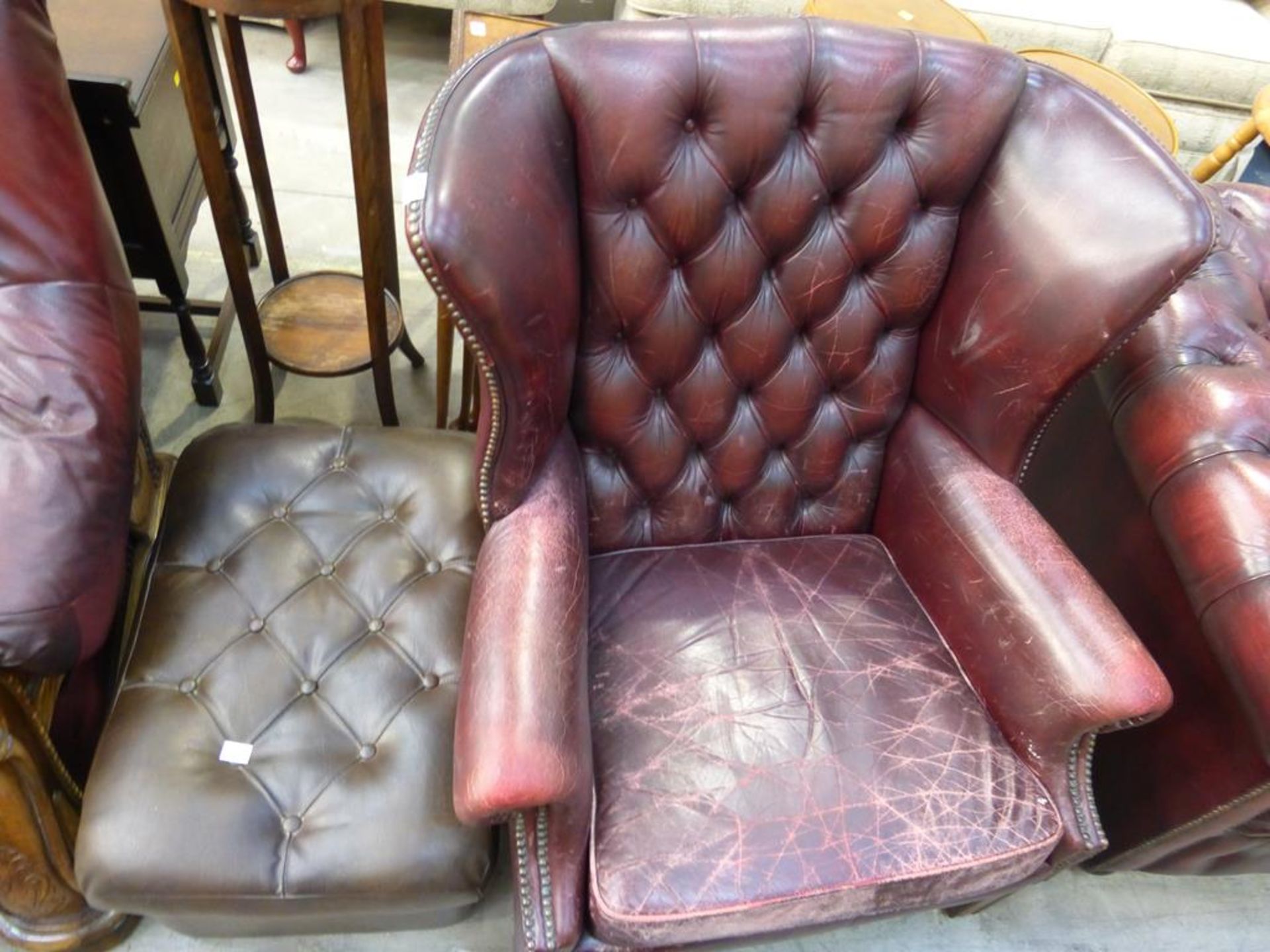 A Georgian Style brown leather buttoned back Wing Armchair together with a similar Pouffe (est £