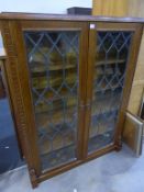 An Oak Display Cabinet or Bookcase with two Leaded Glass Doors enclosing Adjustable Shelves