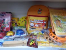 * A shelf containing Child Themed Musical Items including a percussion set, harmonica, ocarinas,