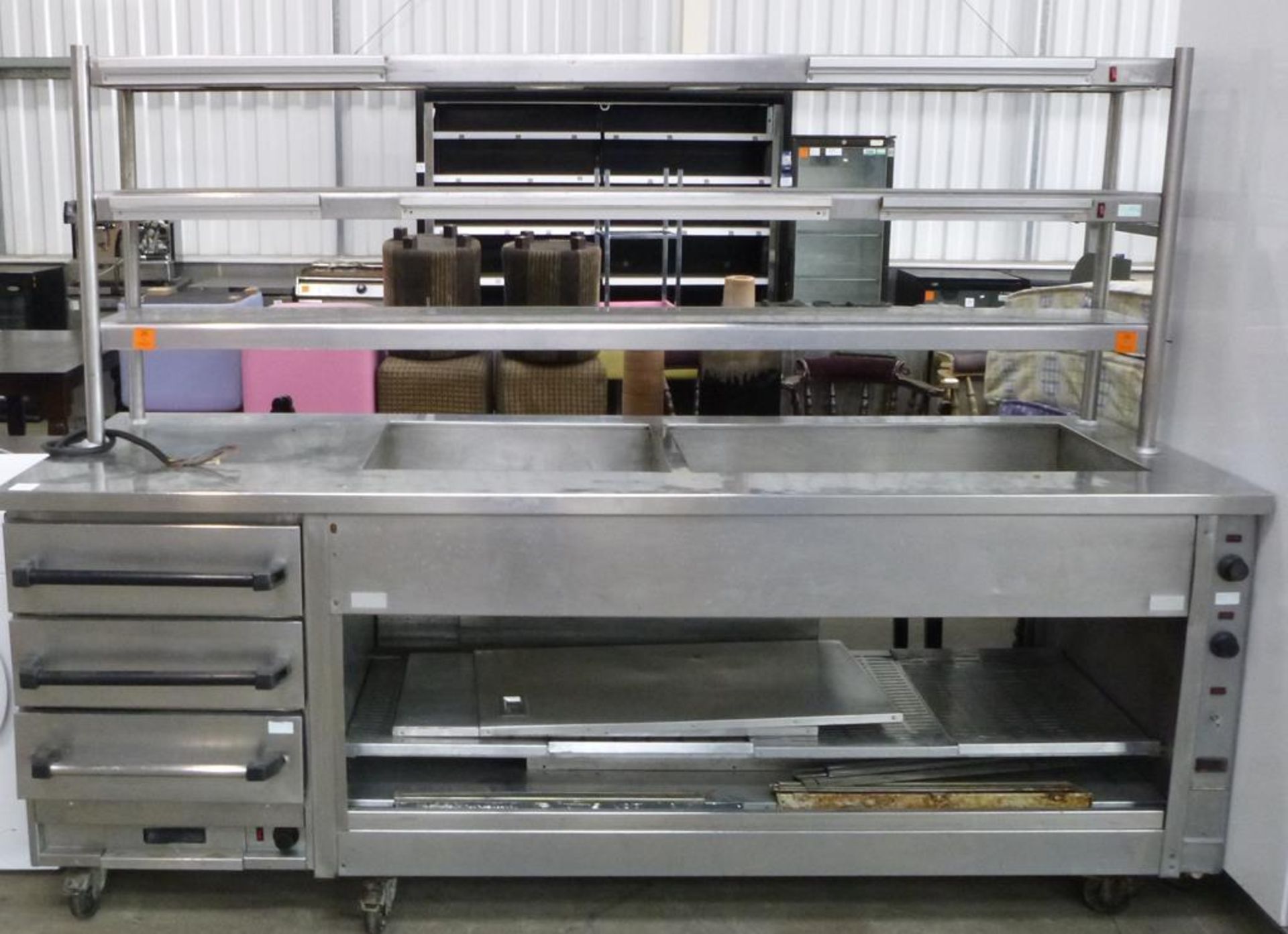 A Large Stainless Steel Heated Serving Counter Unit with 3 Tier Shelving to the top and 3 Drawers to