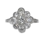 A DIAMOND CLUSTER RING in white gold or platinum, set with nine old cut diamonds in a cluster