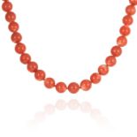 A CORAL BEAD NECKLACE comprising a single row of thirty five polished coral beads of approximately