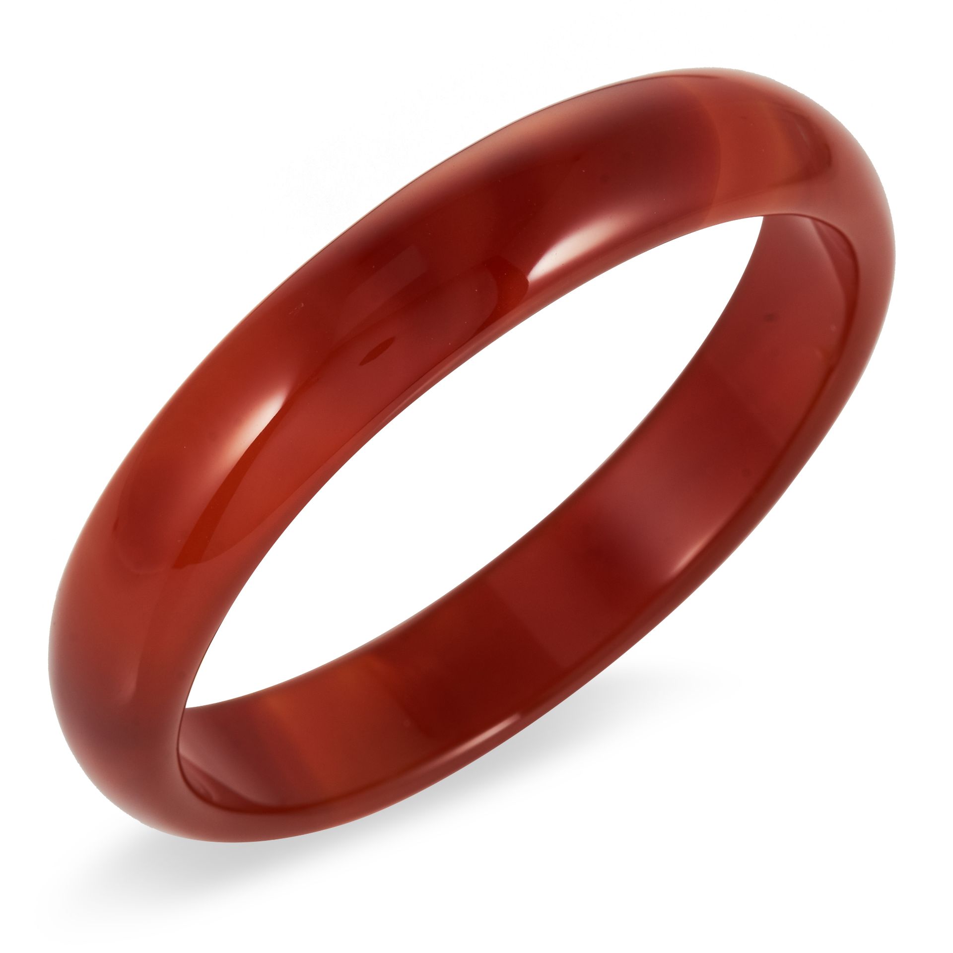 A RED AGATE BANGLE formed of a circular hoop carved from a single piece of agate, inner diameter 6.