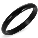 A BLACK AGATE BANGLE formed of a circular hoop carved from a single piece of agate, inner diameter