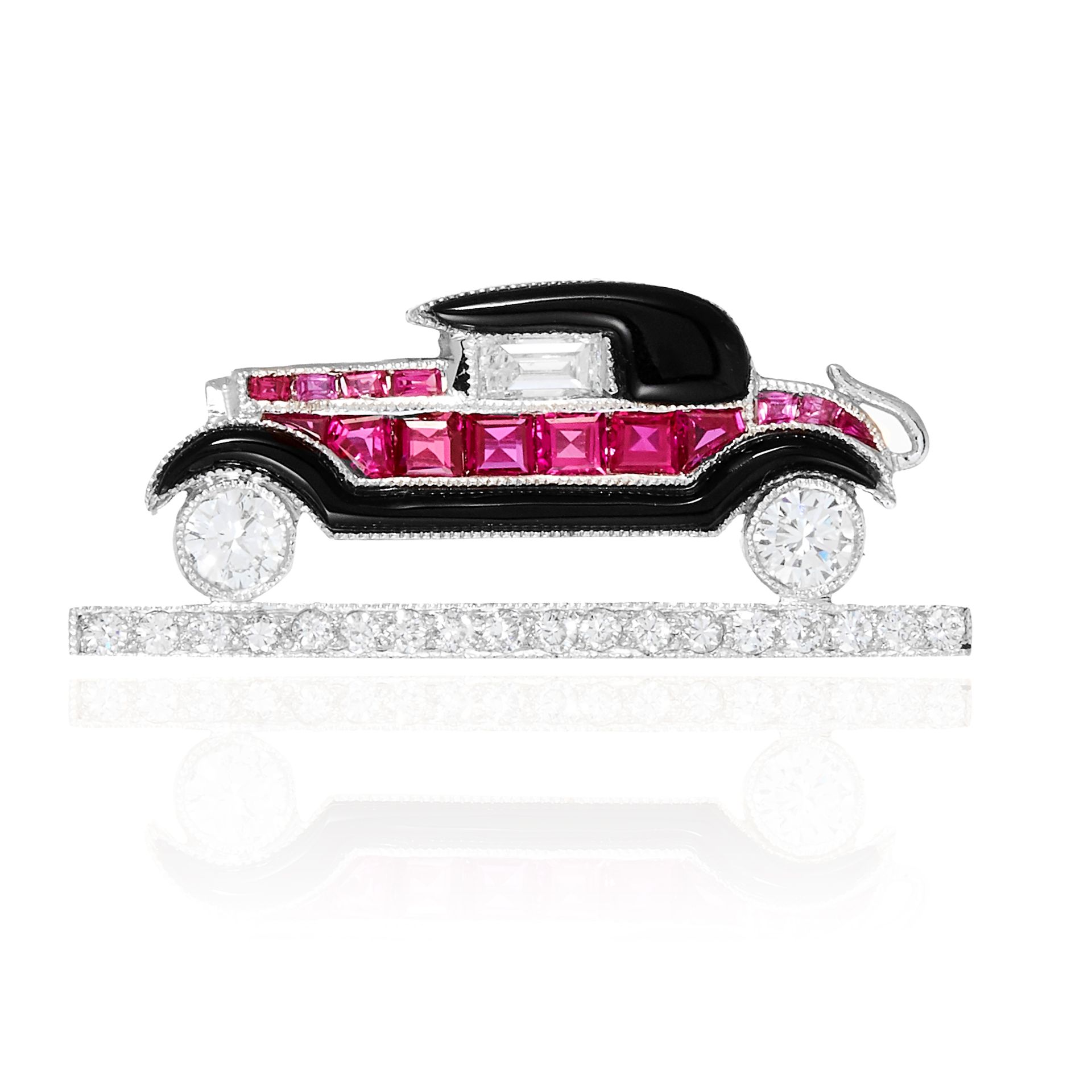 AN ONYX, RUBY AND DIAMOND CAR BROOCH in gold or platinum, jewelled with round cut diamonds,