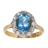 AN AQUAMARINE AND DIAMOND CLUSTER RING in 18ct yellow gold, set with an oval cut aquamarine of