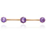 AN ANTIQUE AMETHYST BROOCH in yellow gold, three round cut amethysts set to a plain bar, unmarked,