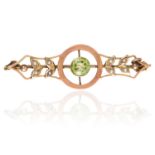 AN ANTIQUE PERIDOT AND PEARL BROOCH in high carat yellow gold, comprising of a central round cut